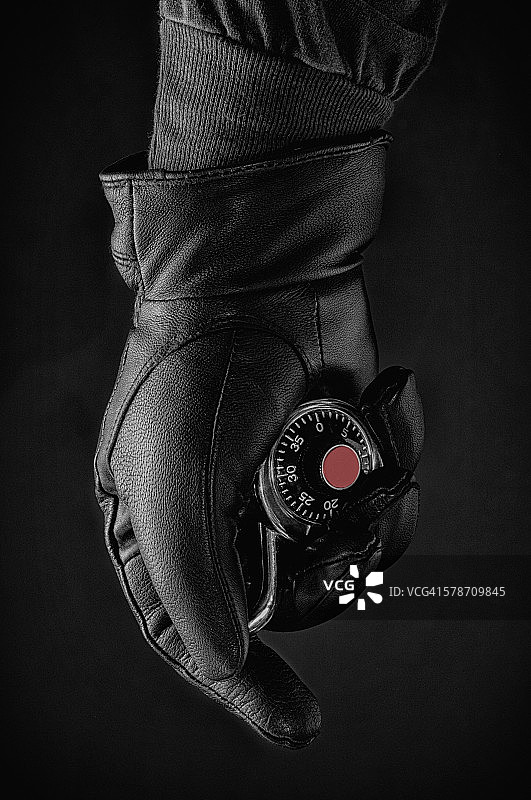 戴着黑色手套的手拿着一把挂锁图片素材