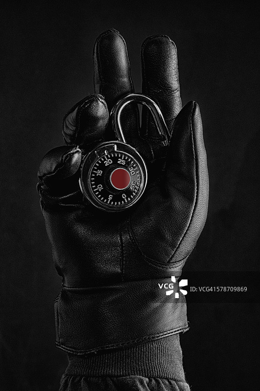 戴着黑色手套的手拿着一把挂锁图片素材
