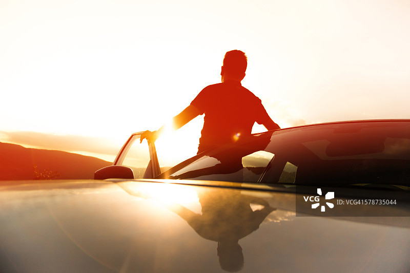 男人在加泰罗尼亚比利牛斯山脉进行SUV公路旅行，沐浴在美丽的日落光芒中图片素材