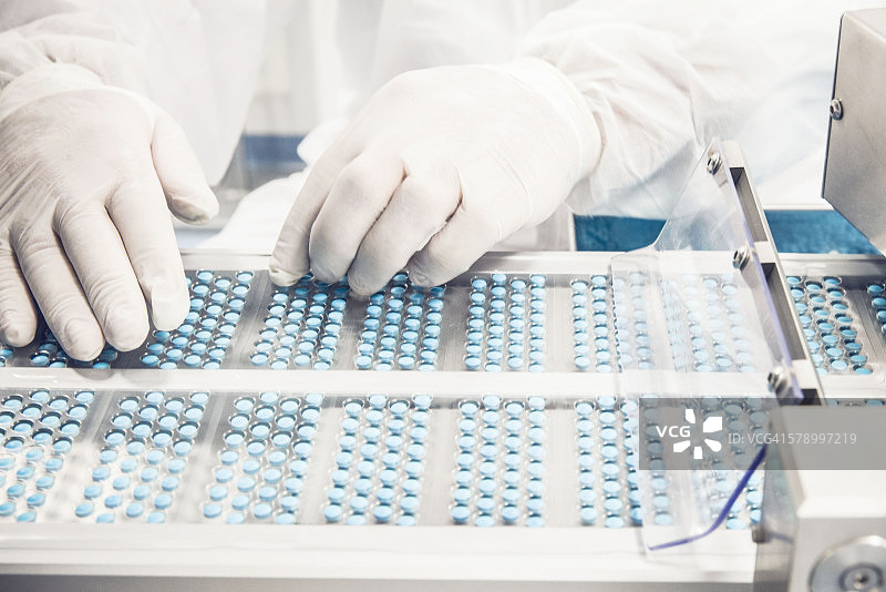 工人检查泡罩包装传送带上的药丸图片素材