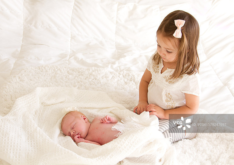 凝视着新生婴儿的小女孩图片素材