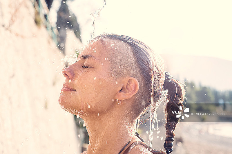 女人站在海滩的淋浴下图片素材