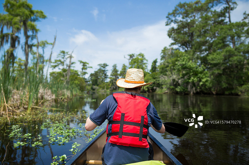 男子在路易斯安那州的湿地划独木舟图片素材