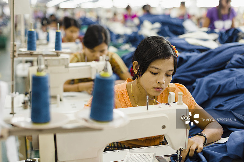 亚洲工人在服装厂缝纫衣服图片素材