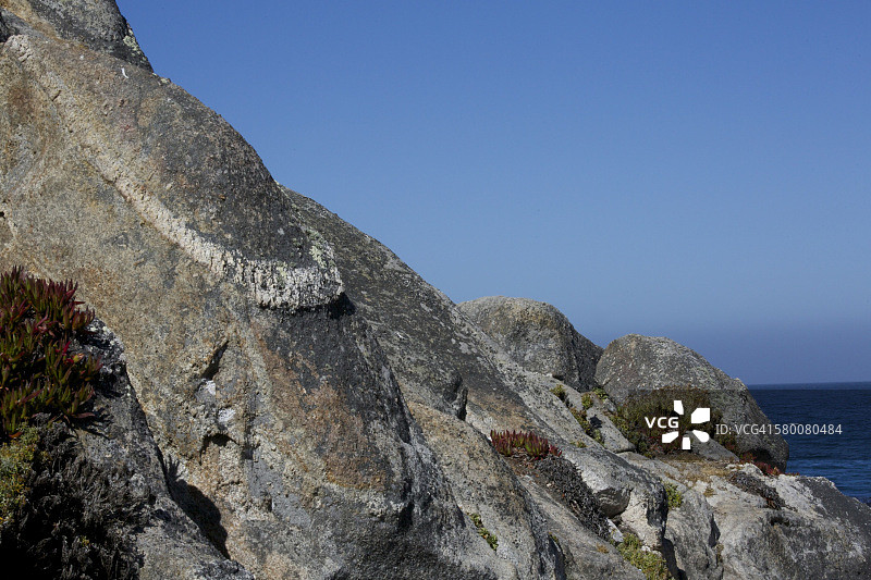 海岸线上岩石的细节，背景是深蓝色大海图片素材