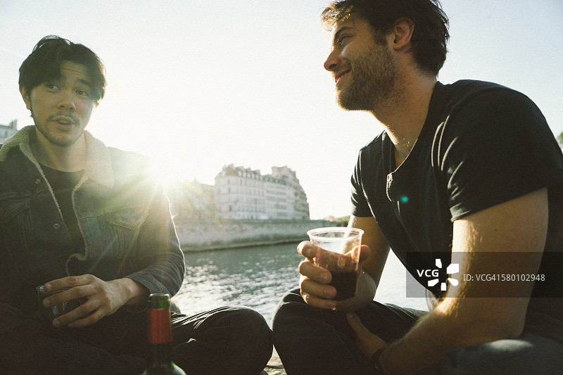 朋友们在日落时分的河边享用美食和葡萄酒图片素材