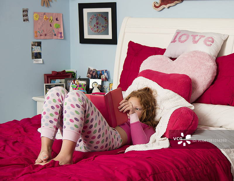 女孩在床上用电子阅读器阅读图片素材