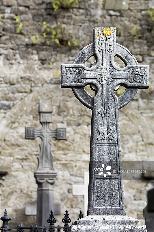 墓地中带有石墙背景的凯尔特十字架的特写图片素材
