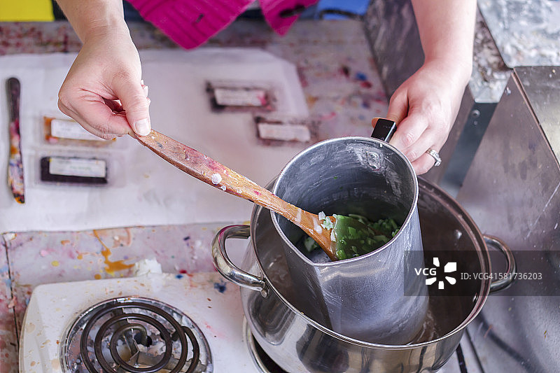 女手工艺人在家演示制作大豆蜡烛的过程，展示炉子上融化的蜡图片素材