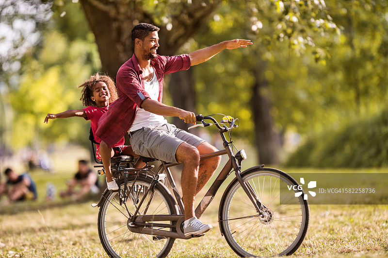 快乐的非裔父女在公园骑自行车图片素材