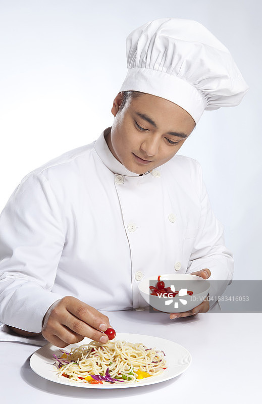 厨师将圣女果放在面条盘上图片素材