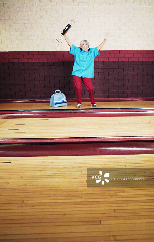 年长的女人手持保龄球奖杯图片素材