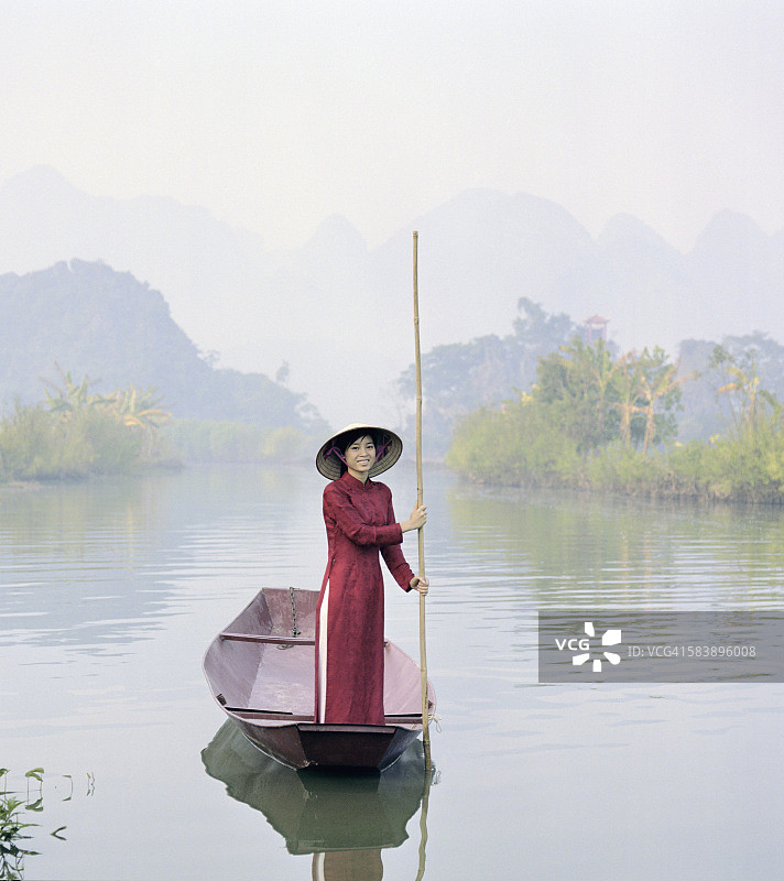 年轻的越南女人在河中驾驶平底船图片素材