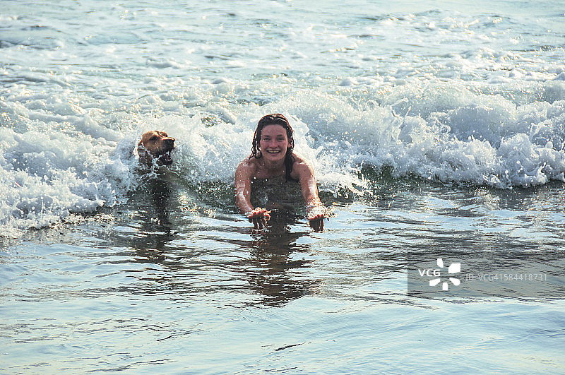 年轻女子与金毛寻回犬一起游泳图片素材