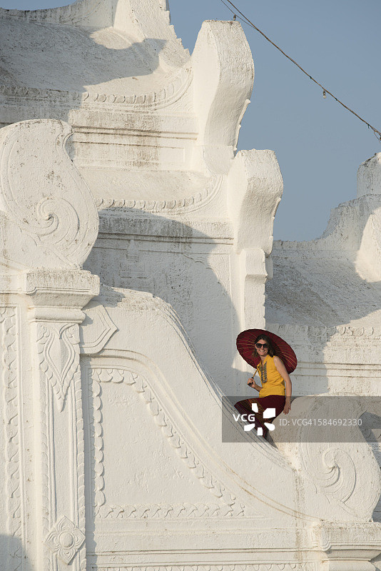 坐在辛比梅白色佛塔下的撑红伞女游客图片素材