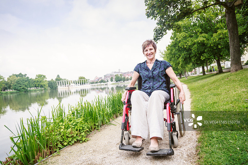 坐在轮椅上在公园享受一天的老年妇女图片素材