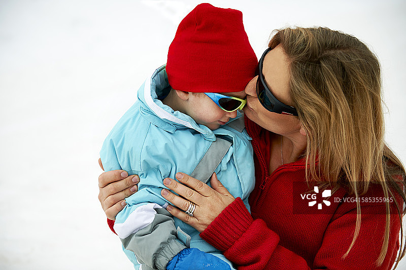 滑雪的母亲亲吻幼儿儿子的额头图片素材