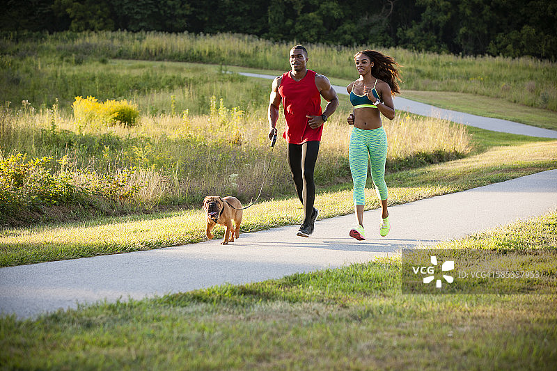 年轻情侣与在公园奔跑的狗图片素材