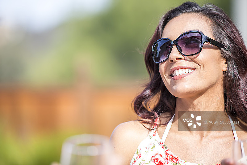 戴着太阳镜的快乐年轻女子在花园里的肖像图片素材