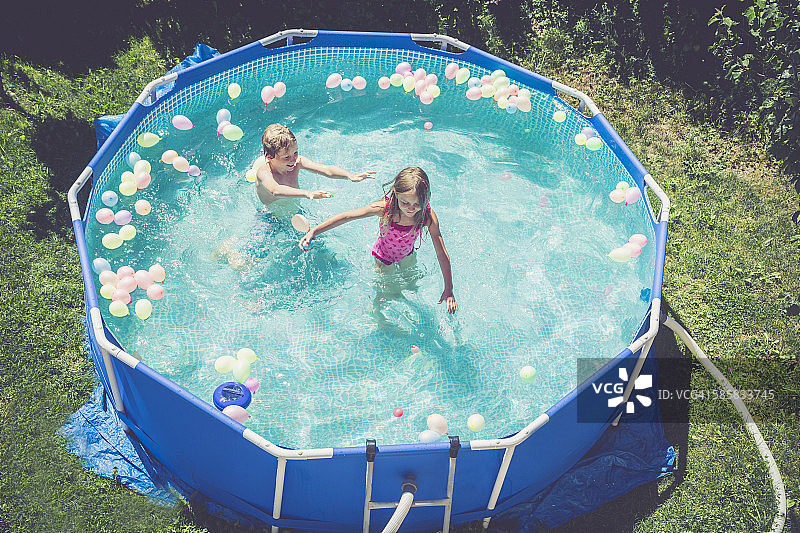 男孩女孩在气球环绕的游泳池中图片素材