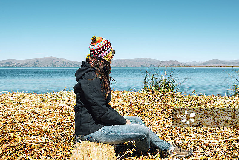 秘鲁普诺，妇女戴着丘约帽坐在的的喀喀湖的漂浮岛上图片素材