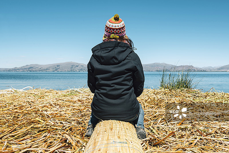秘鲁普诺，妇女戴着丘约帽坐在的的喀喀湖的漂浮岛上图片素材