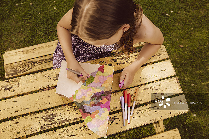女孩在花园里的木制杂志文件上绘画图片素材