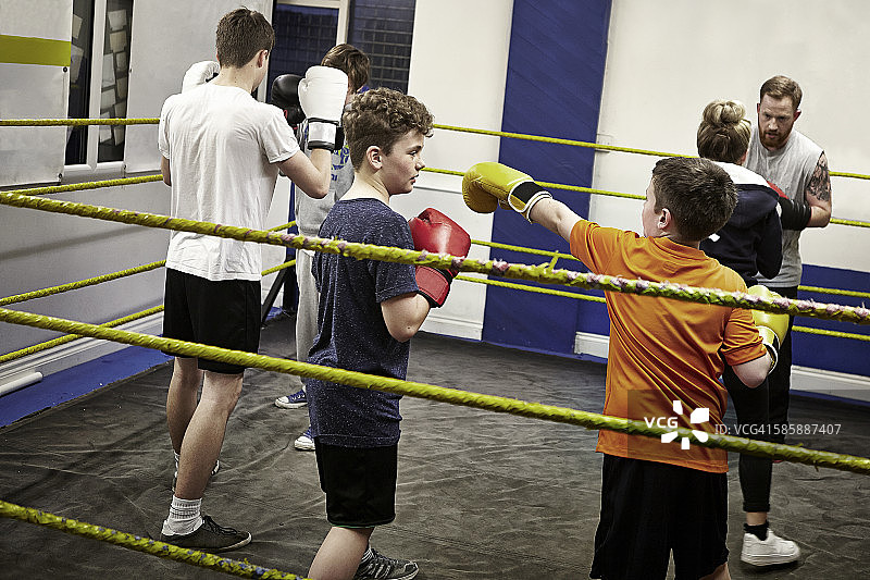 儿童拳击俱乐部成员在拳击台训练图片素材