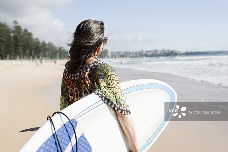 女人在海滩上 carrying her surfbard图片素材