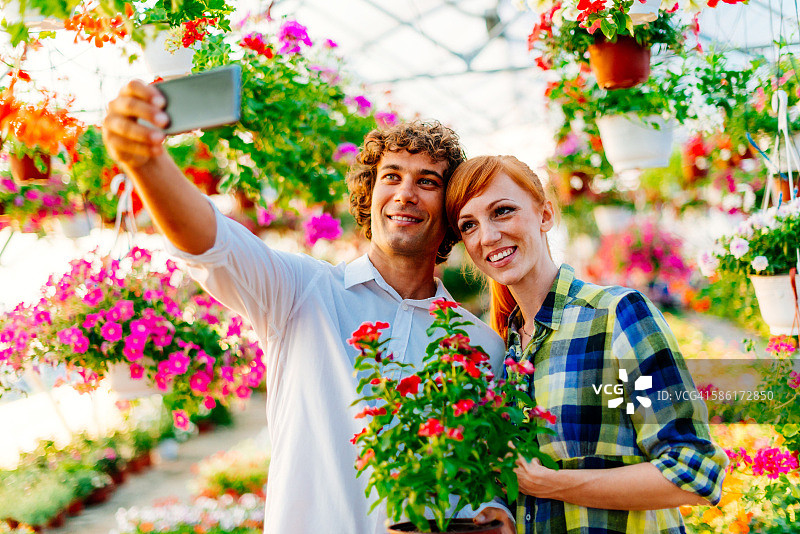 年轻情侣在植物苗圃中与盆栽合影图片素材
