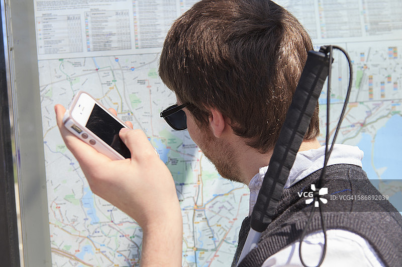年轻盲人在公交车站使用辅助技术查看地图图片素材