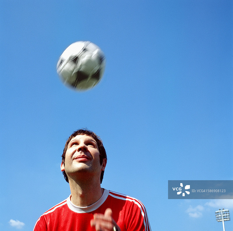 年轻男人用头顶足球图片素材
