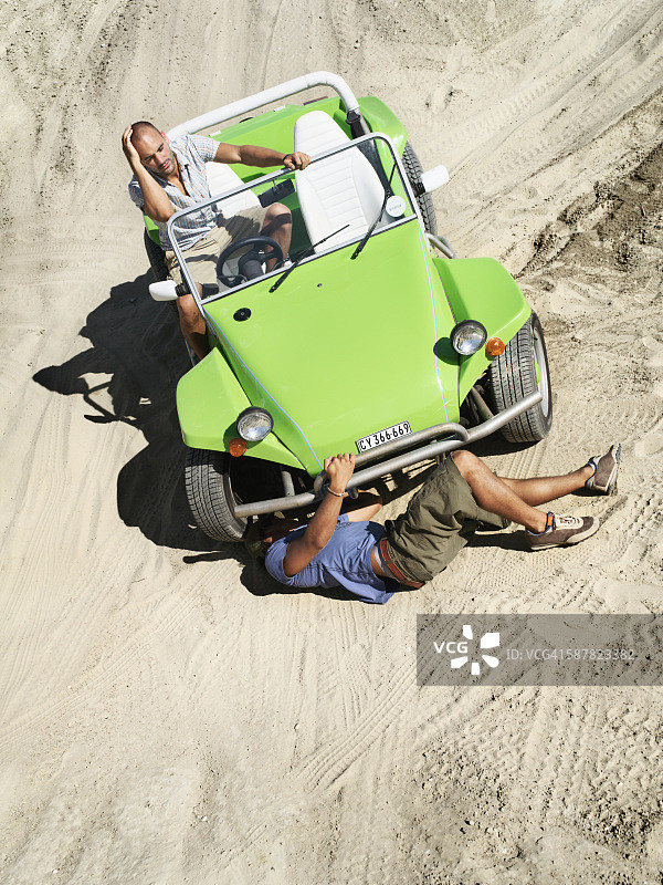 沙丘上和损坏的沙丘越野车旁的男人图片素材