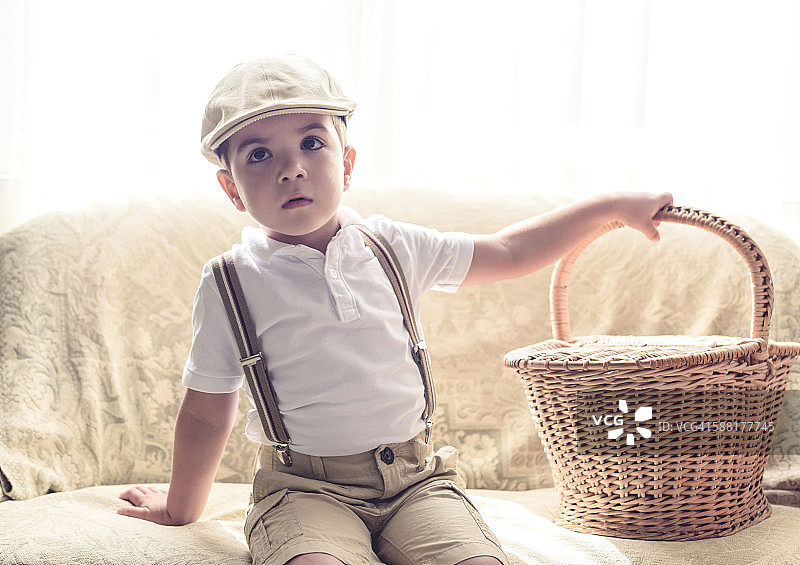 抱着篮子坐着的小男孩肖像图片素材