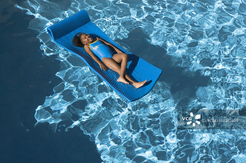 女孩在泳池的气垫床上放松图片素材