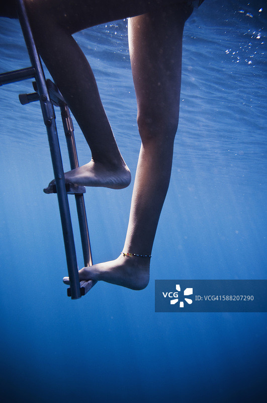 少女攀爬双体船梯子的水下视角图片素材