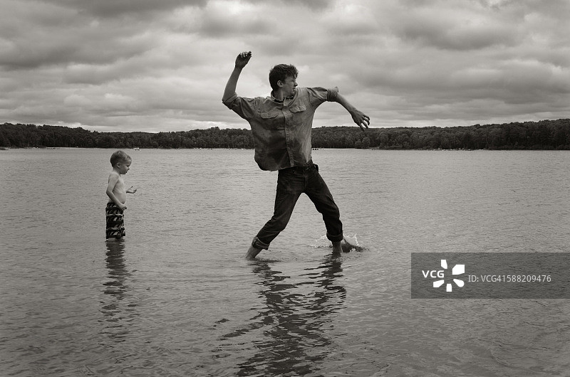 在湖中打水漂，身后站着一个男孩图片素材