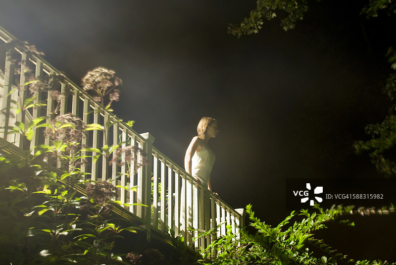 年轻女子在夜晚的阳台上图片素材
