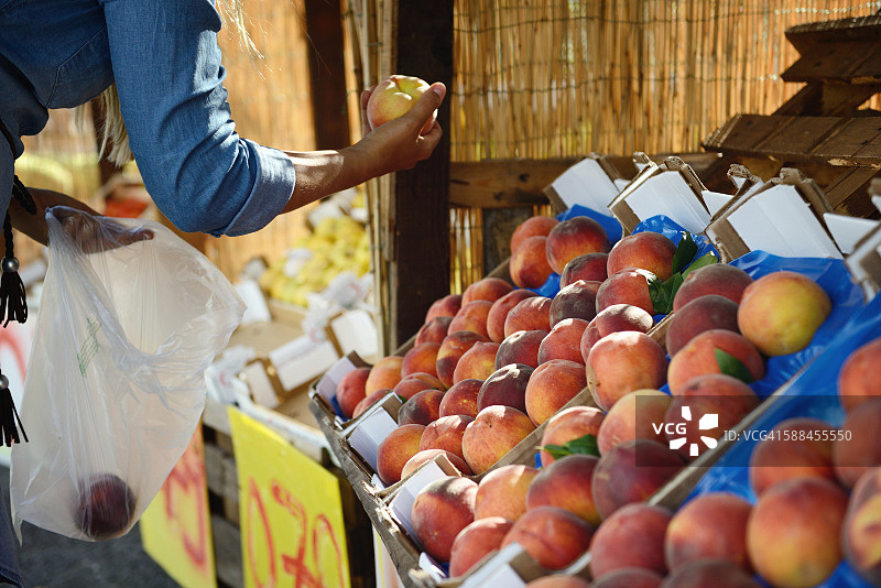 手在农贸市场挑选成熟的桃子图片素材