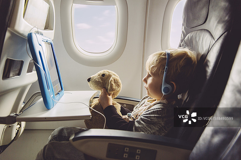 小男孩坐在飞机上看平板电脑图片素材