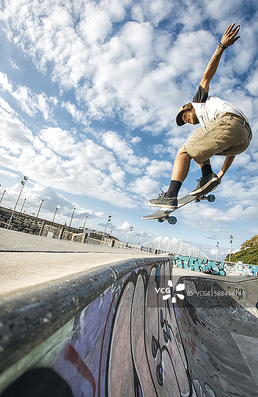 年轻滑板手在滑板公园腾空跳跃图片素材