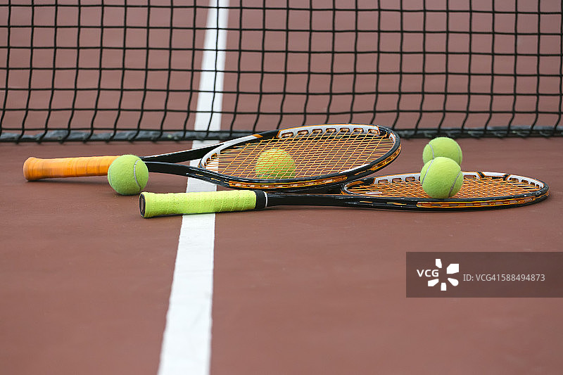 两只网球拍和四个网球，位于网球场地地面上图片素材