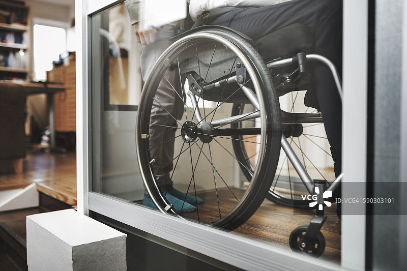 坐轮椅的父子在家中使用升降机图片素材