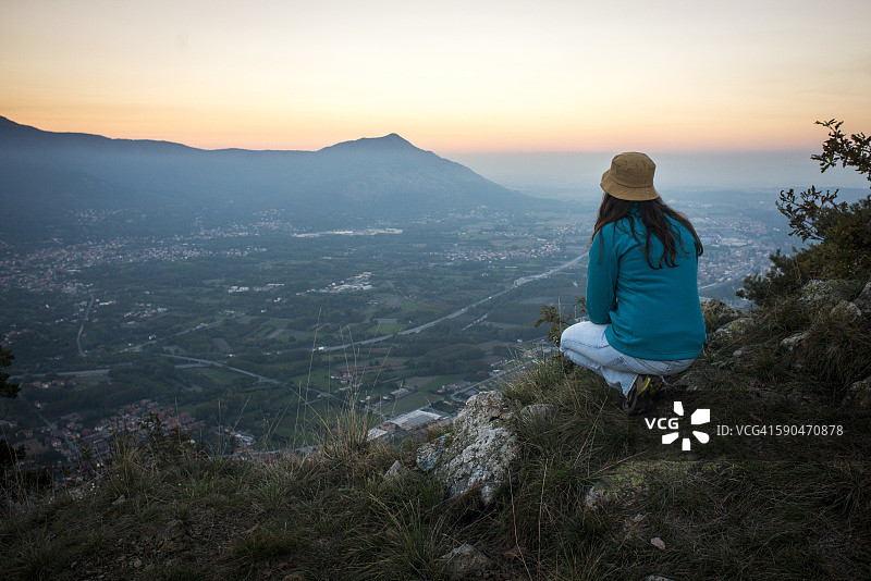 日落时分，站在悬崖边眺望山谷的年轻女子（背影）图片素材
