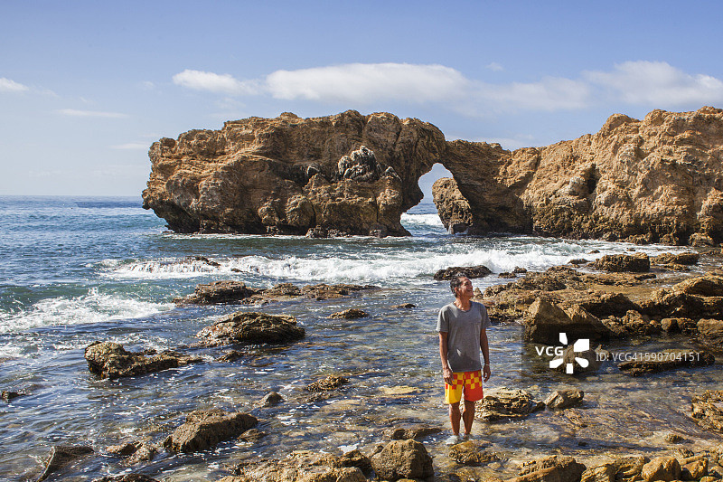 男子站在壮丽海岸线的水中图片素材