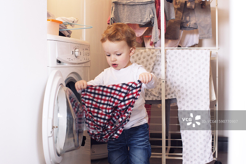 小男孩从烘干机里拿出衣服图片素材