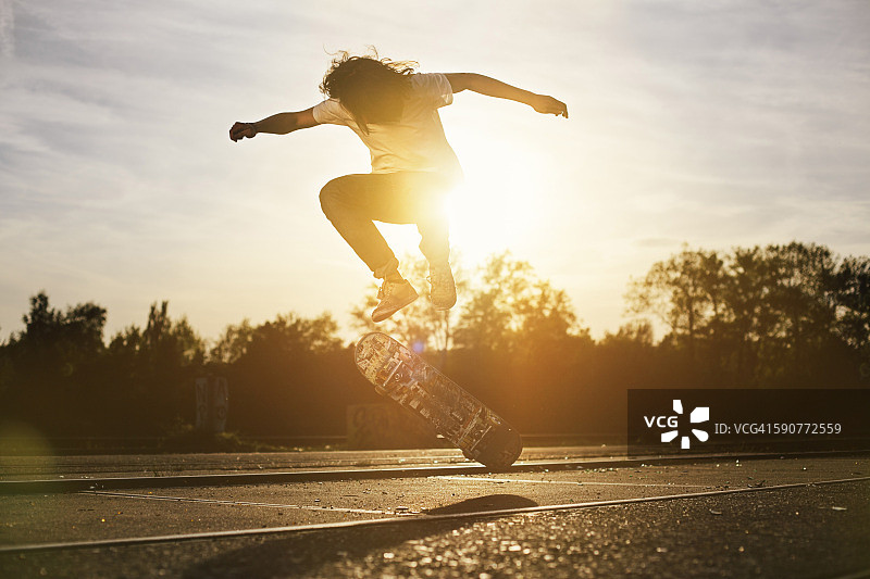 逆光下玩滑板的年轻男人图片素材