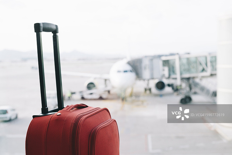 机场的红色行李箱，背景是飞机图片素材