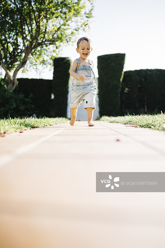 小男孩赤脚在花园的地板上奔跑图片素材