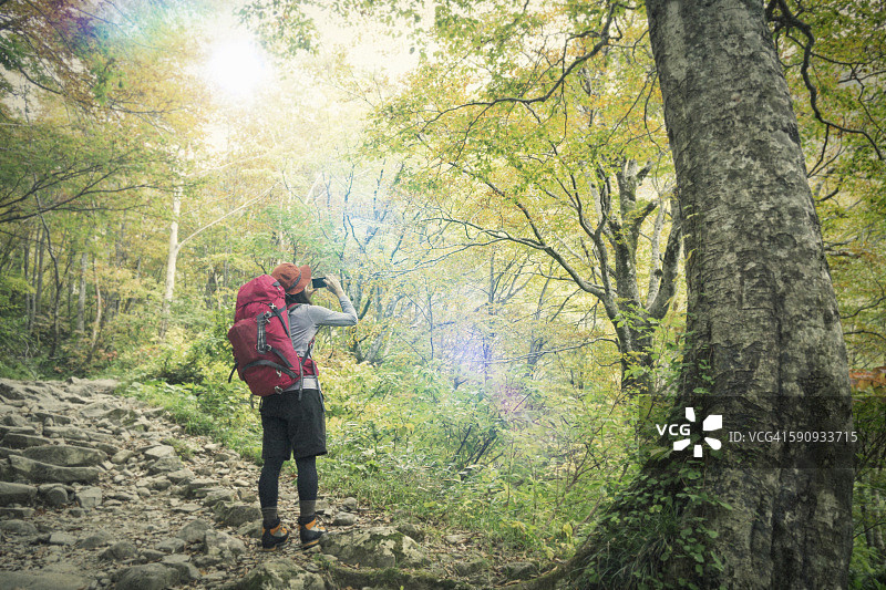 用智能手机拍摄山景照片的女人图片素材